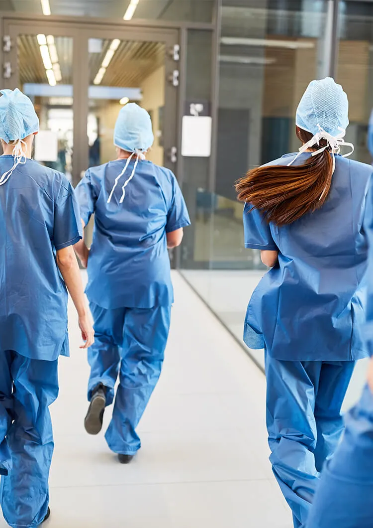 Personnel soignant courant dans un couloir d’hôpital en tenue médicale bleue